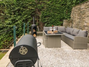 An outdoor patio with a grill, wicker furniture, and a stone wall. - 1 Orchard View (Hope Valley)