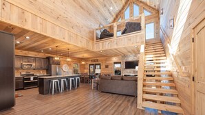 A spacious wooden cabin with a kitchen, dining area, and a loft bedroom. - New Luxury 5 BR Cabin w/ Incredible Views, Hot Tub, Wi-Fi, Arcade, Pool Table (Sevierville)