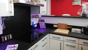 A modern kitchen with white cabinets, a black countertop, and a red accent wall.