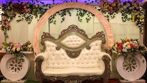 Un sofá lujoso con intrincados adornos, ubicado debajo de un arco floral.