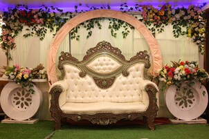 A luxurious sofa with ornate carvings, positioned under a floral arch.