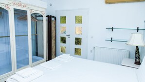 A hotel room with a large bed, a wardrobe with glass doors, a door with frosted glass panels, a radiator, and a lamp on a bedside table. - Chic Charming Central Athens Apt. (Athens)