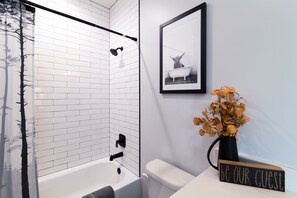 Bathroom features a shower enclosure, bathtub, and towel rack.