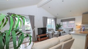 A spacious living area with a sofa, television, and a dining area with a kitchen counter. - Hillside View (Morpeth)