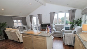 A spacious living area with a kitchen island, a sofa, and a chair. - Hillside View (Morpeth)