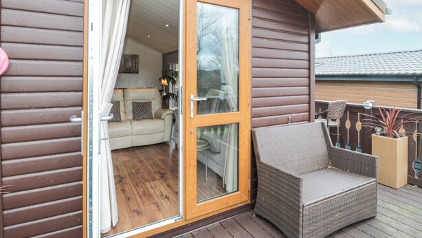 A wooden cabin with a sliding glass door leading to a living area with a sofa and a table. - Hillside View (Morpeth)