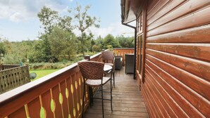 A wooden deck with a view of a green landscape and trees. - Hillside View (Morpeth)