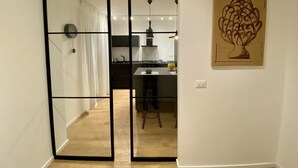 A modern kitchen with a dining area, a sliding glass door leading to another room, and a framed artwork on the wall.