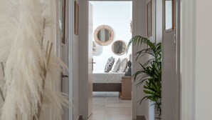 A hallway leading to a bedroom with a bed, bedside tables, and decorative mirrors. - Villa Samiram (Ierapetra)