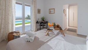 A hotel room with a bed, a desk, and a view of the sea. - Villa Samiram (Ierapetra)