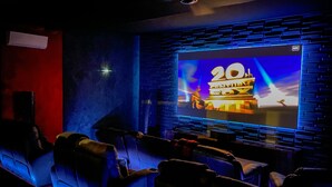 A cinema with a large screen, rows of seats, and a brick wall design.