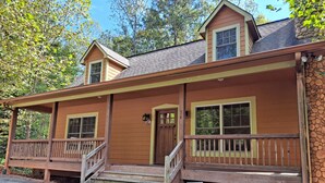 A cabin with a porch, a front door, and a sign indicating it is a cabin rental.