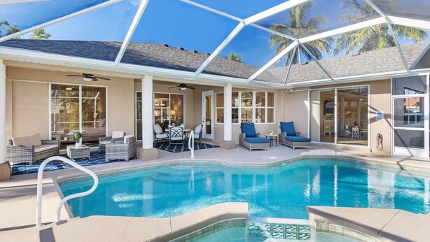 A pool area with a glass-enclosed patio, lounge chairs, and a ceiling fan.