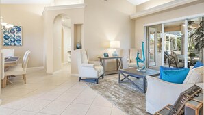 A spacious living room with a dining area, a large window, and a view of the outdoors.
