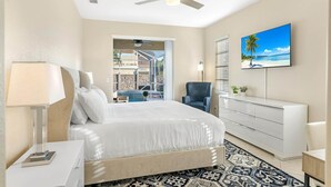 A bedroom with a bed, a ceiling fan, a TV, a desk, and a window with a view of a pool and outdoor area.