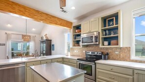 Une cuisine moderne dotée d’un grand îlot central, d’un four à micro-ondes encastré, d’un four et de placards.
