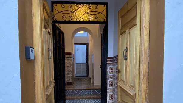 A narrow hallway with patterned tile flooring, wooden doors, and a tiled wall. - Traveler's House (Setenil de las Bodegas)