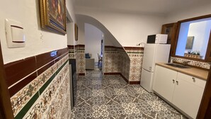 A narrow hallway with patterned tile flooring, a white refrigerator, and a sink on the right. - Traveler's House (Setenil de las Bodegas)