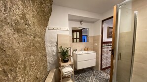 A bathroom with a bathtub, a sink, a mirror, and a shower area. - Traveler's House (Setenil de las Bodegas)