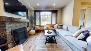A living room with a fireplace, a sofa, a coffee table, and a TV. - Pet-Friendly Luxury, Bright Interior, On Golf Course! Private Gas Grill (Mammoth Lakes)