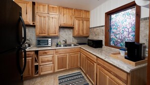 A kitchen with wooden cabinets, a toaster, a kettle, a sink, and a window with a stained glass view. - Pet Friendly Cabin on 3.5 acres between Durango and Purgatory - Fire Pit (Durango)