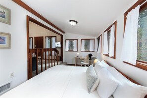A bedroom with a large bed, a desk, and a chair. There are windows with curtains, a door, and a ceiling light. - Pet Friendly Cabin on 3.5 acres between Durango and Purgatory - Fire Pit (Durango)