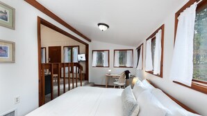 A bedroom with a large bed, a desk, and a chair. There are windows with curtains, a door, and a ceiling light. - Pet Friendly Cabin on 3.5 acres between Durango and Purgatory - Fire Pit (Durango)