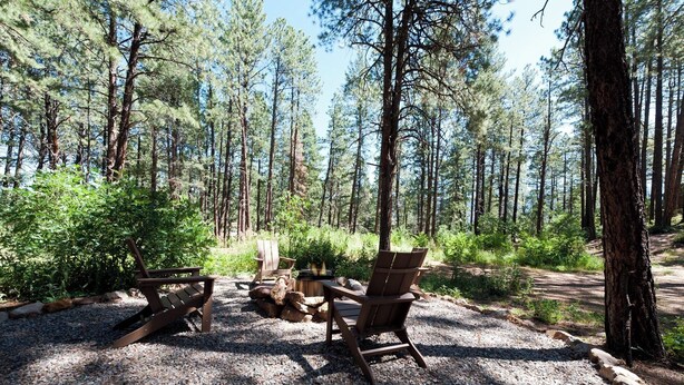 A forested area with a gravel path, wooden chairs, and a fire pit. - Pet Friendly Cabin on 3.5 acres between Durango and Purgatory - Fire Pit (Durango)