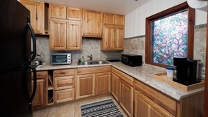 A kitchen with wooden cabinets, a toaster, a kettle, a sink, and a window with a stained glass view. - Pet Friendly Cabin on 3.5 acres between Durango and Purgatory - Fire Pit (Durango)