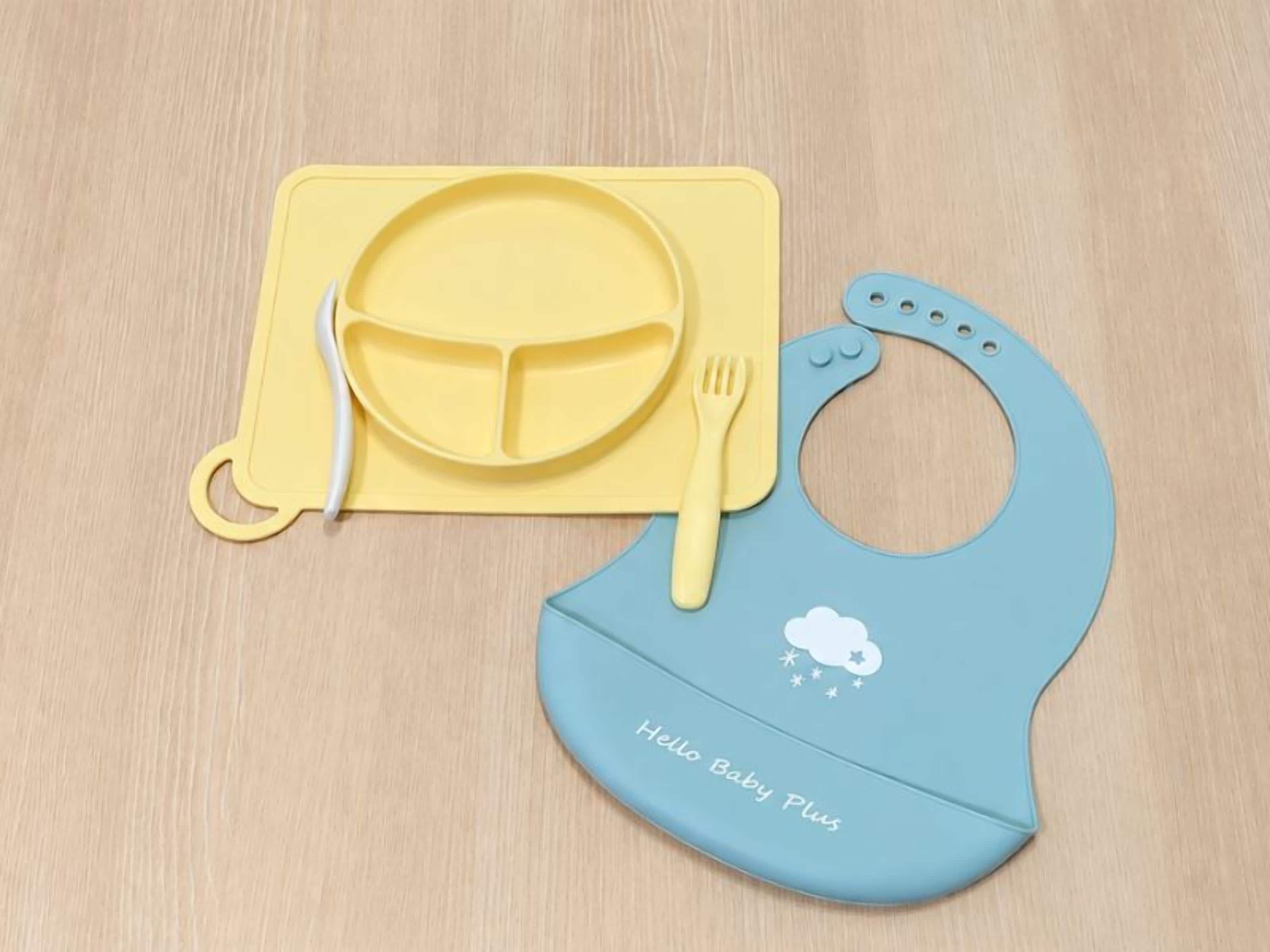 A baby bib and a yellow placemat with a plate and fork.