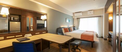 Una habitación de hotel con cama, escritorio, silla y un espejo grande.