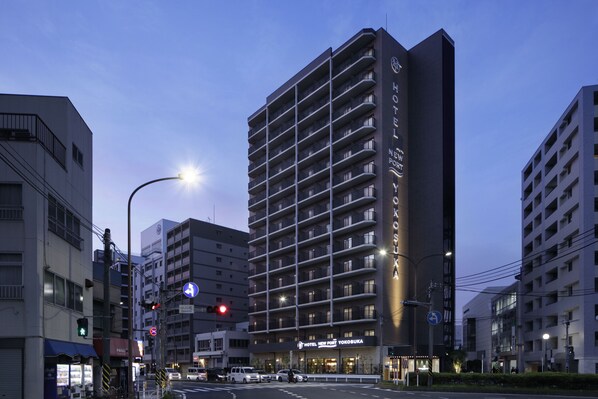 Un hotel de varios pisos con diseño moderno, que cuenta con balcones y un letrero llamativo.