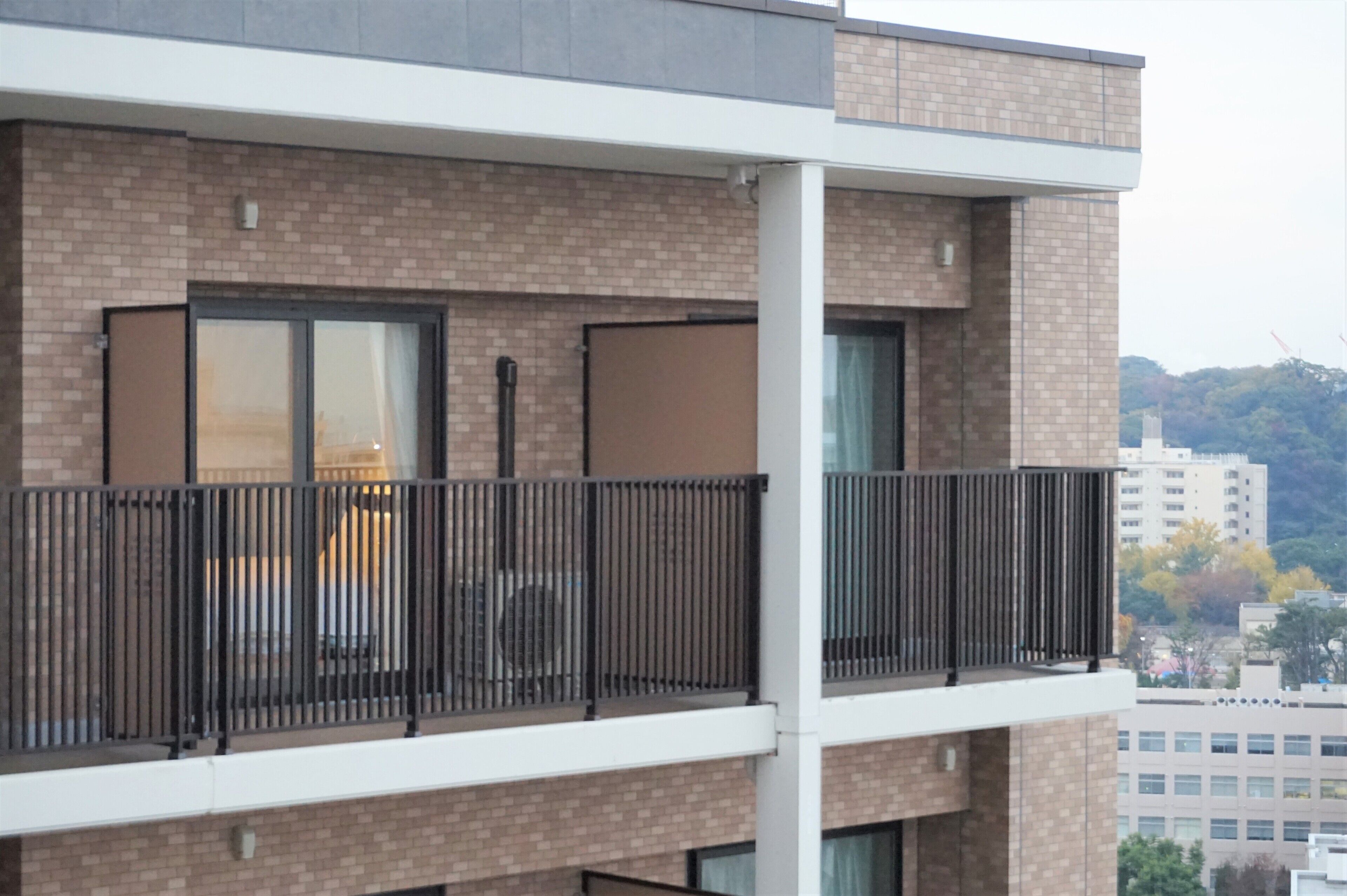 A multi-story building with a brick facade and balconies with metal railings.