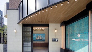 La entrada del Hotel New Port Yokosuka, con un diseño moderno, una pintura de barco y un letrero.