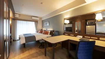 A hotel room with a bed, desk, chair, and a large mirror.