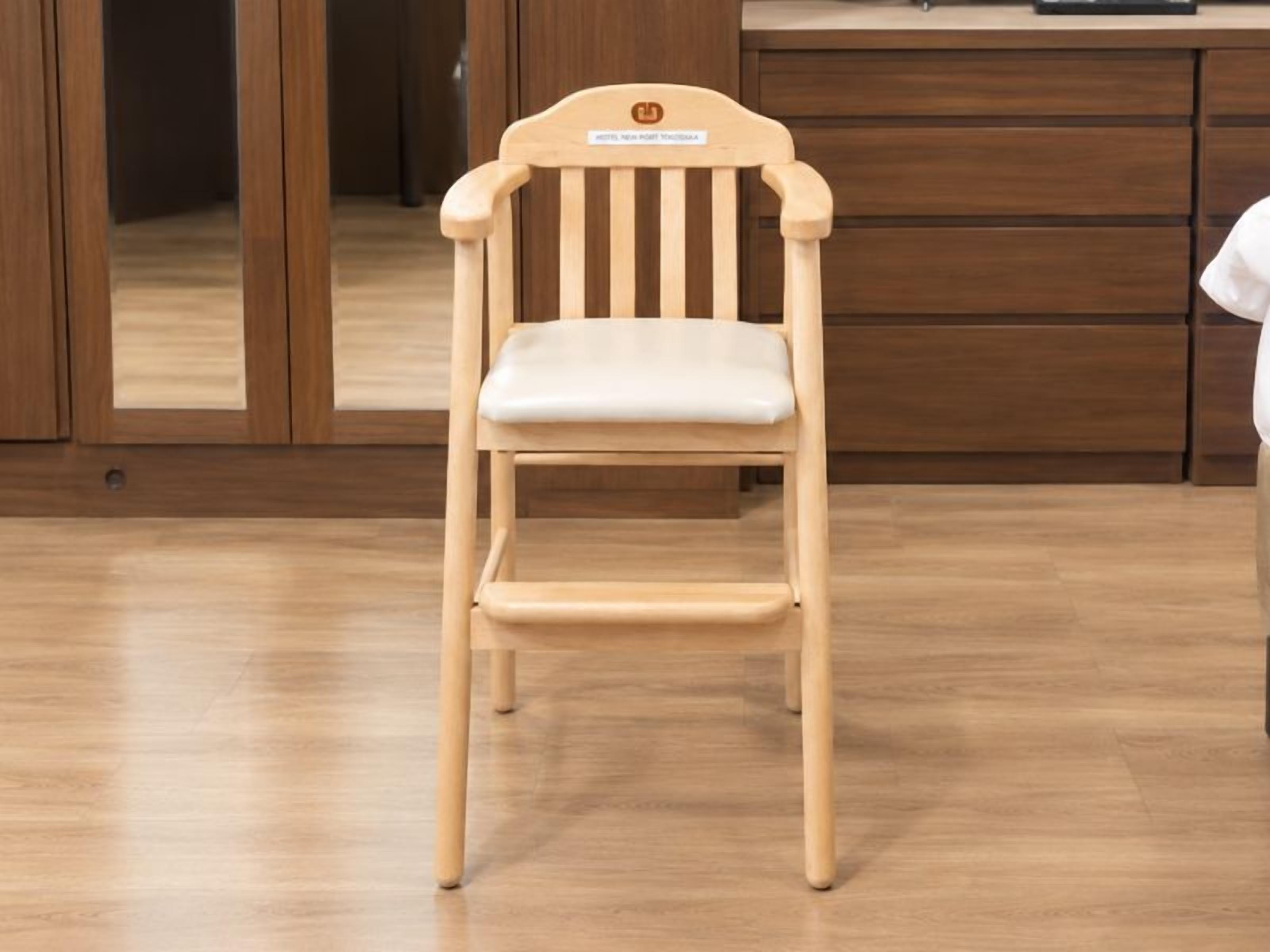 Una silla de madera con asiento y respaldo acolchados, ubicada en una habitación con piso y armarios de madera.