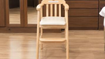 Una silla de madera con asiento y respaldo acolchados, ubicada en una habitación con piso y armarios de madera.