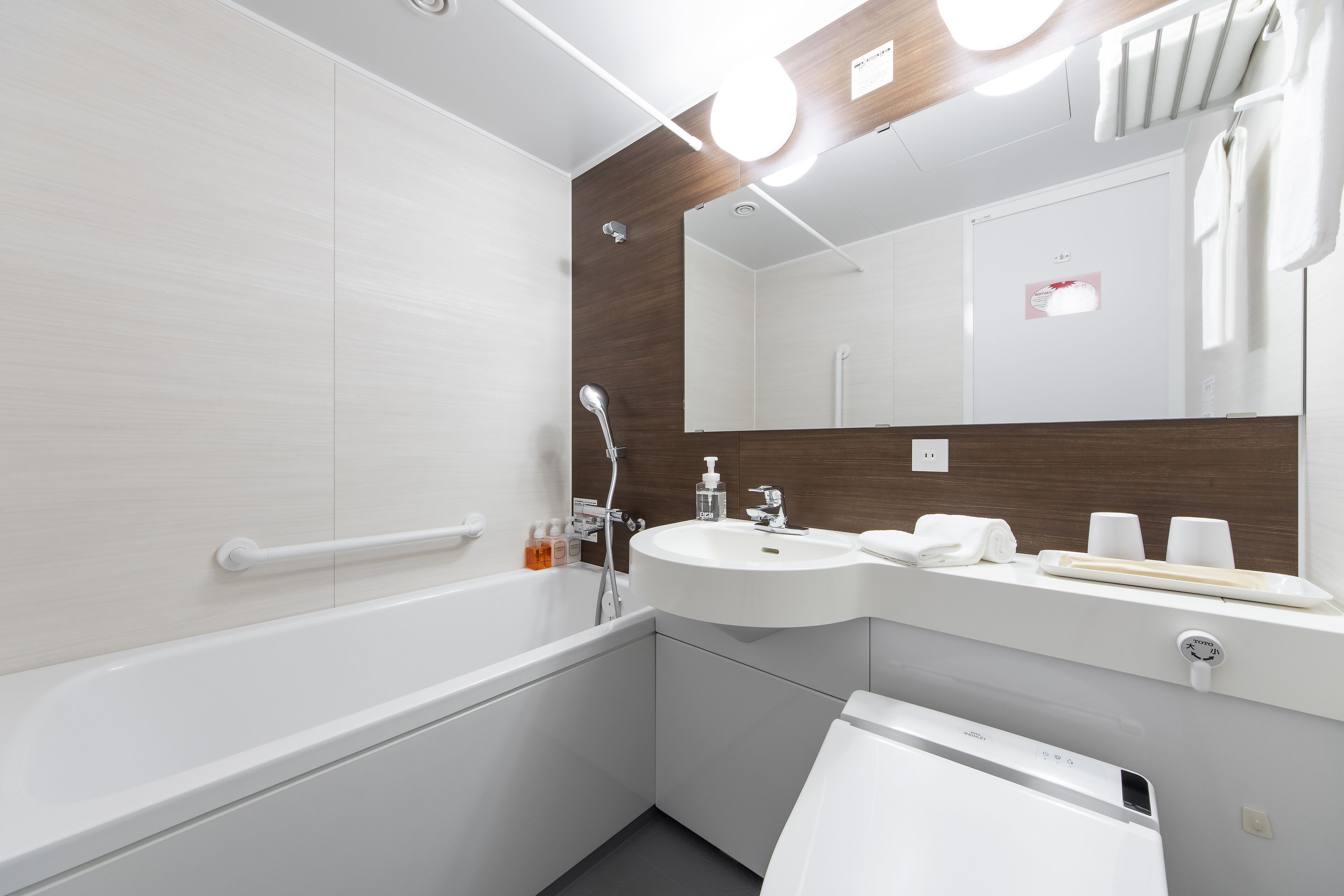 A modern bathroom with a bathtub, a sink, a mirror, and a towel rack.