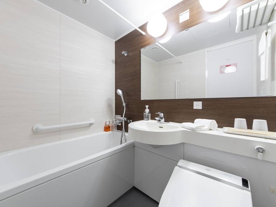 A modern bathroom with a bathtub, a sink, a mirror, and a towel rack.