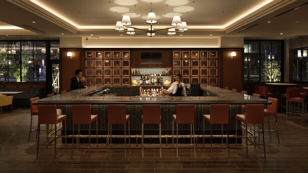 Zona de bar moderna con una barra central, taburetes y un bartender.