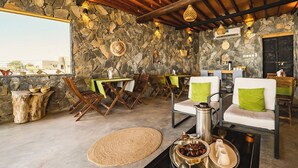Un interior rústic amb parets de pedra, bigues de sostre de fusta i una combinació de seients, com ara cadires i sofàs.