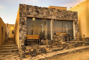A stone building with a wooden bench and a rope barrier. - SAMA Heritage Home - Al Khutaim (Al Hamra)
