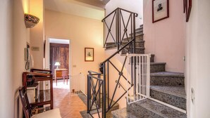 Una escalera con barandilla de metal, un banco de madera y un comedor con mesa y sillas.