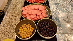 A buffet table with various food items, including sliced cucumbers, tomatoes, and olives, in a hotel setting.