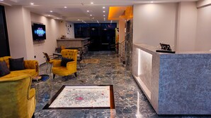 A hotel lobby with a reception desk, seating area, and a television screen.