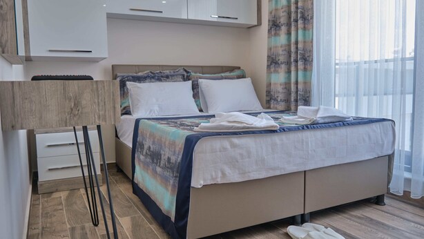 A modern hotel room with a bed, a desk, and a chair.