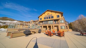 A large building with multiple balconies, outdoor seating, and a view of a snowy mountain. - Balcony with Views | Hot Tub & Firepit Enjoyment (Keystone)