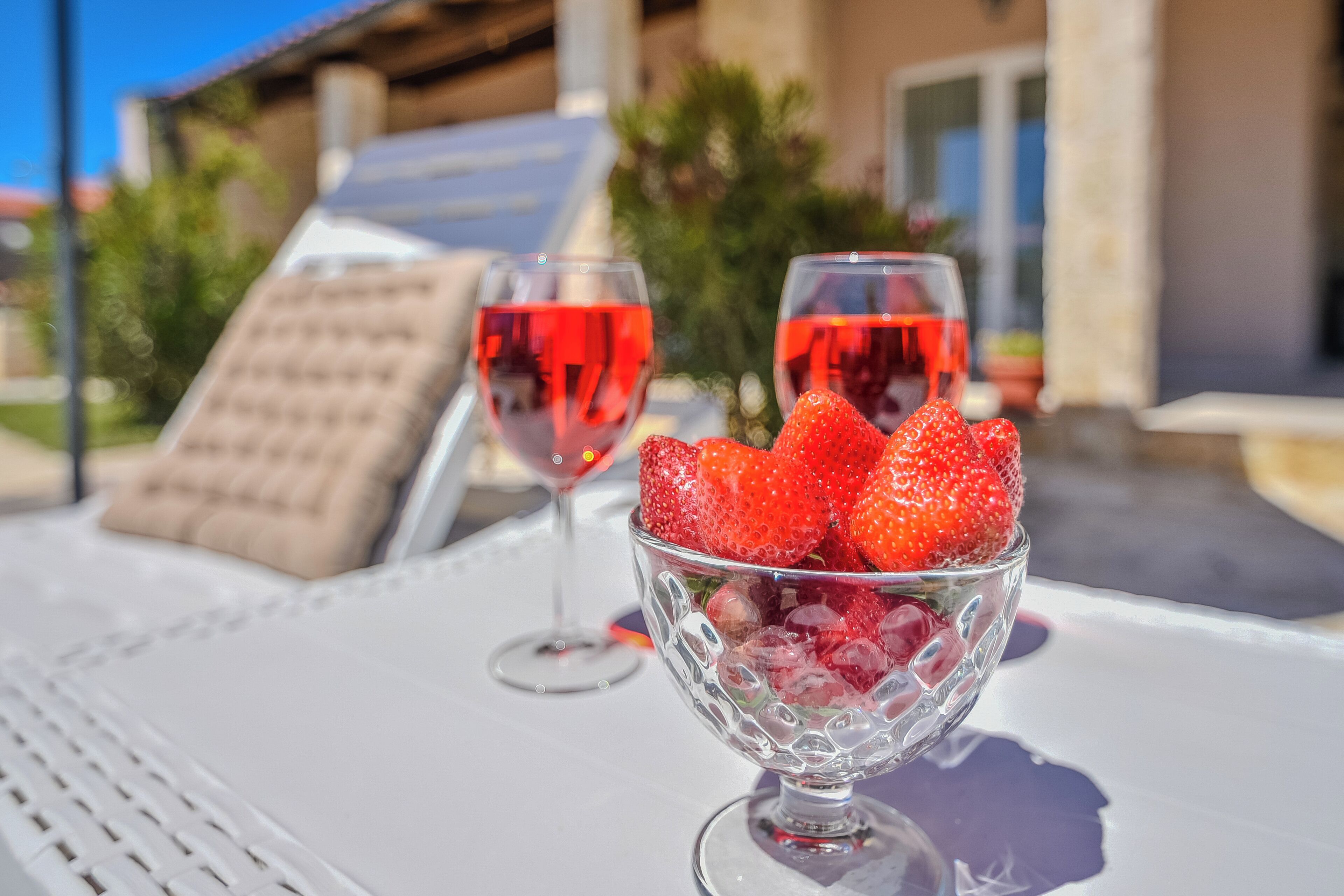 Ein Tisch mit einer Glaskugel voller Erdbeeren und zwei Weingläsern.
