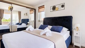 Ein Hotelzimmer mit einem großen Bett, einem Nachttisch mit Lampe, einem Spiegel und einem Fenster mit Jalousien.