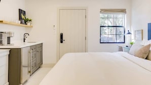 Ein Schlafzimmer mit Bett, Nachttisch, Fenster und Tür.